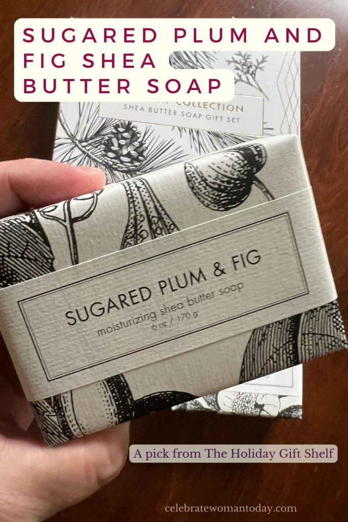 Hand holding a wrapped Sugared Plum and Fig soap bar in front of the Holiday Collection gift box