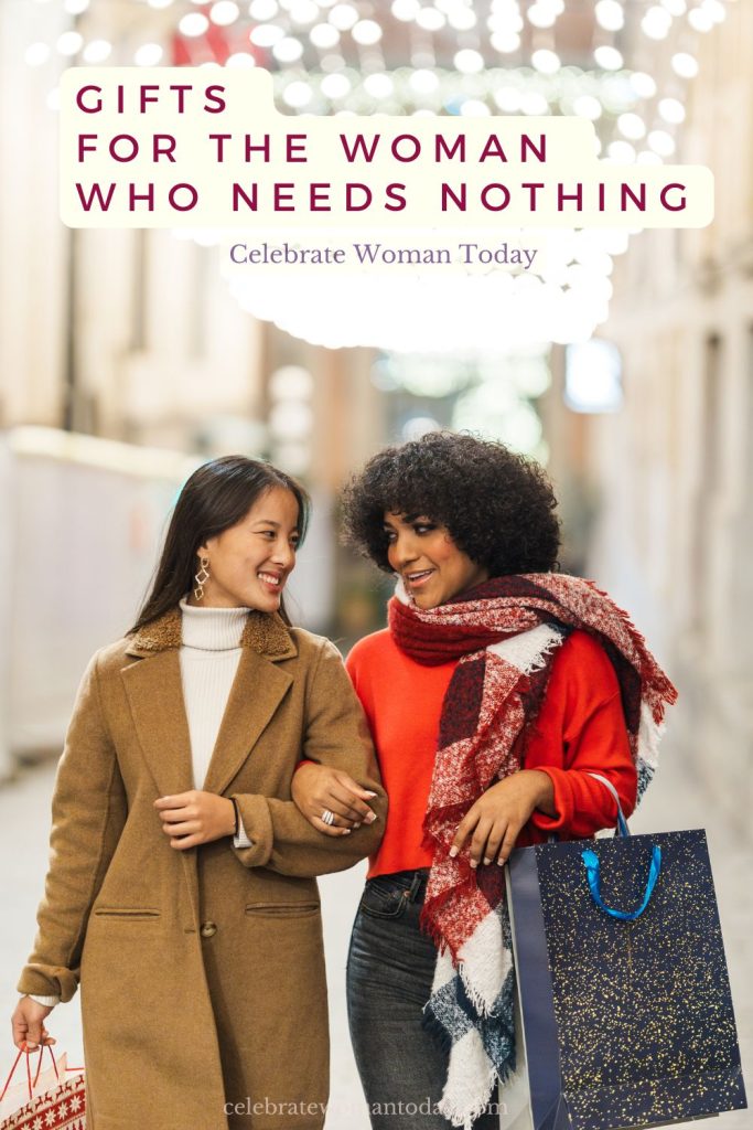 Gift ideas for women in menopause: two friends walking arm in arm under holiday lights with shopping bags